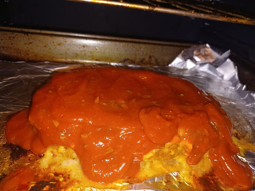 cheeseburger meatloaf in oven with glaze poured on top